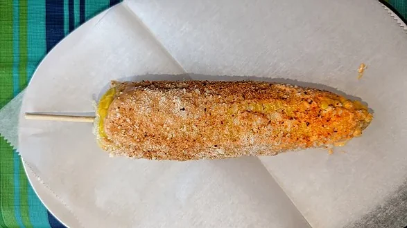 トウモロコシに串をさしマヨネーズなどで味付けする